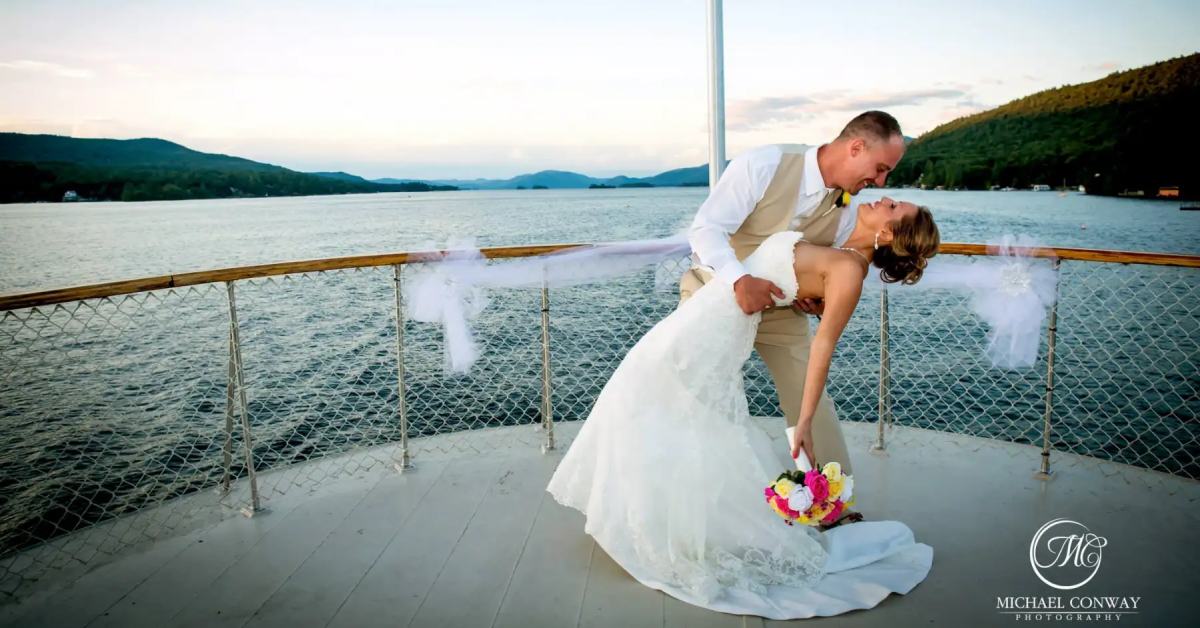 couple kissing in wedding attire at the front of a boat