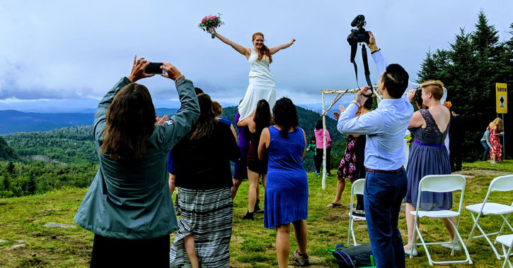 a bride being held up on a mountain for a photo op