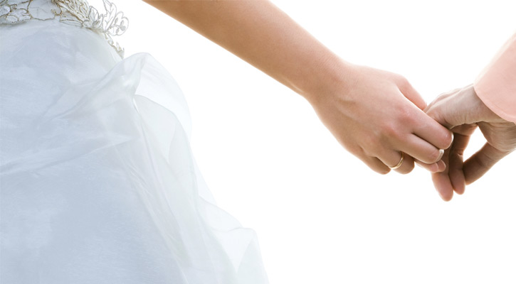 close up of a bride just barely holding the groom's hand