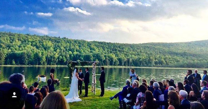 a couple getting married in front of a lake on a beautiful day