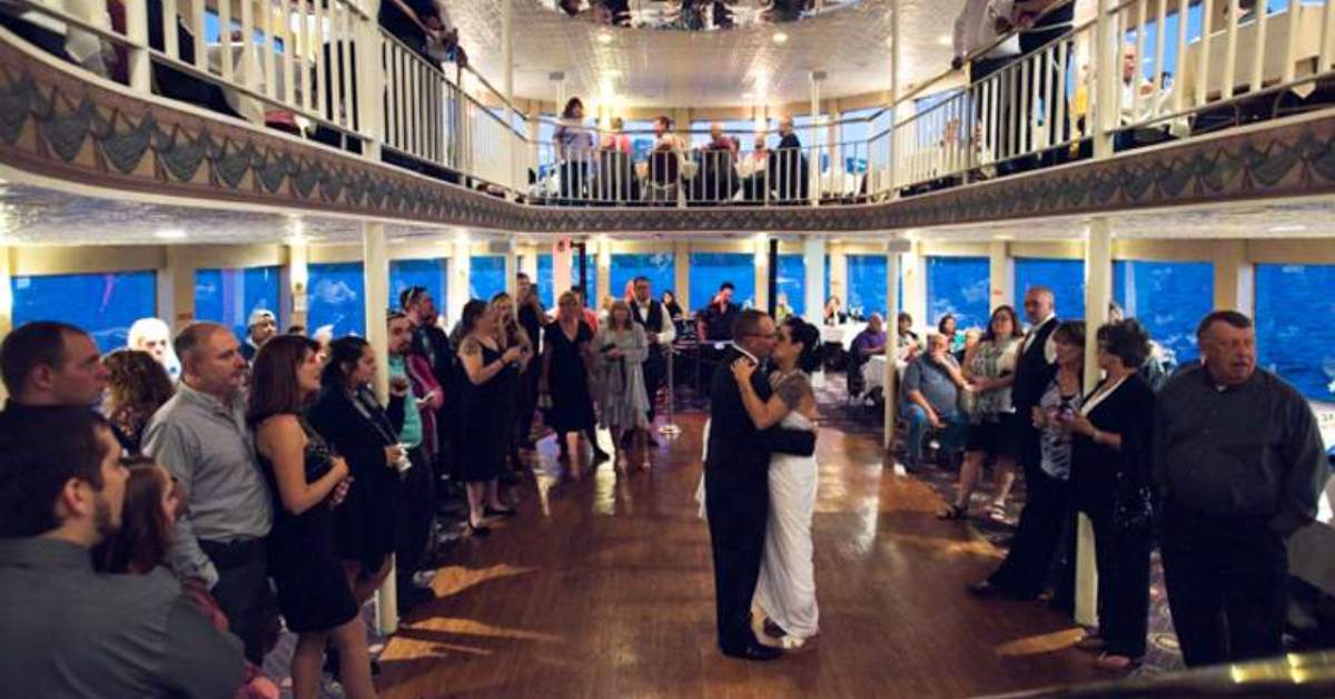 a couple dancing inside a boat while onlookers smile